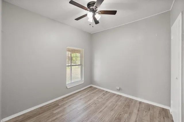 an empty room with ceiling fan and window