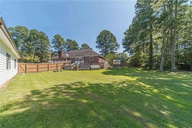 a view of a house with wooden deck and a backyard