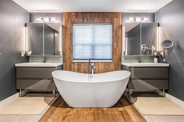 a bathroom with a tub a mirror and a shower