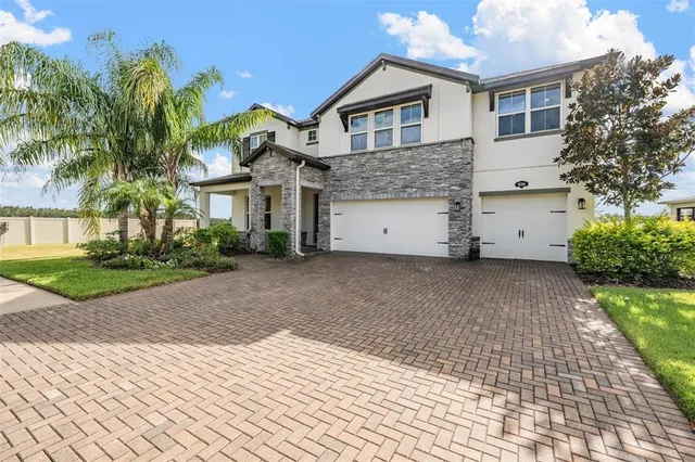 a view of a white house with a small yard and large trees