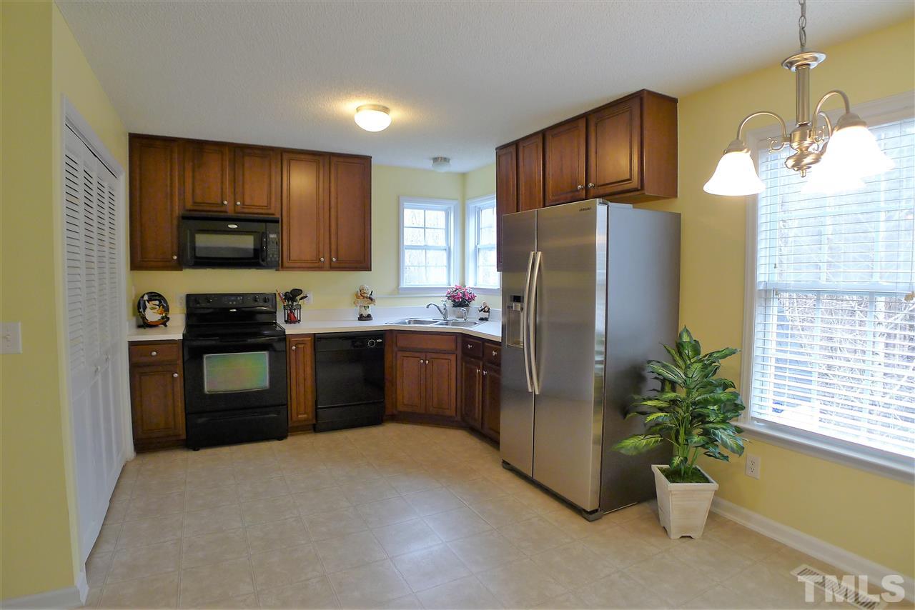 208 Muirfield Ridge Drive Garner, NC 27529 - Photo 11 of 30 a kitchen with stainless steel appliances kitchen island granite countertop a refrigerator a stove a sink a window with wooden floor and cabinets