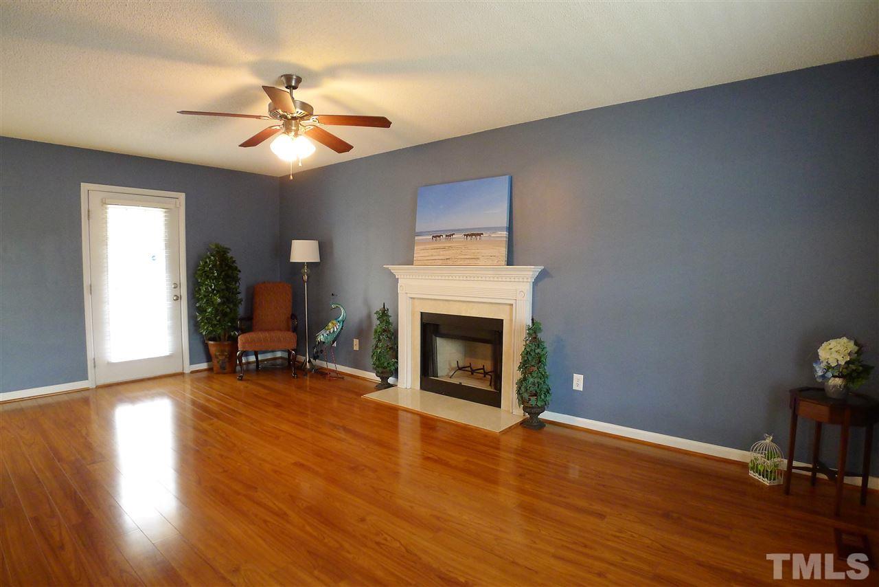 208 Muirfield Ridge Drive Garner, NC 27529 - Photo 5 of 30 a view of a livingroom with a fireplace a ceiling fan and wooden floor