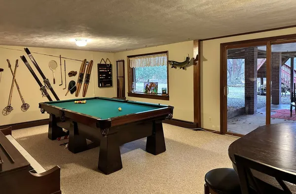 a room with furniture pool table wooden floor and windows