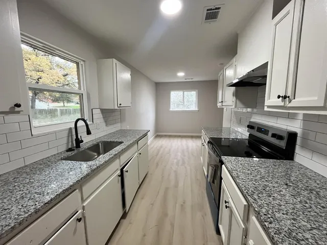 a kitchen with stainless steel appliances granite countertop a sink stove and cabinets