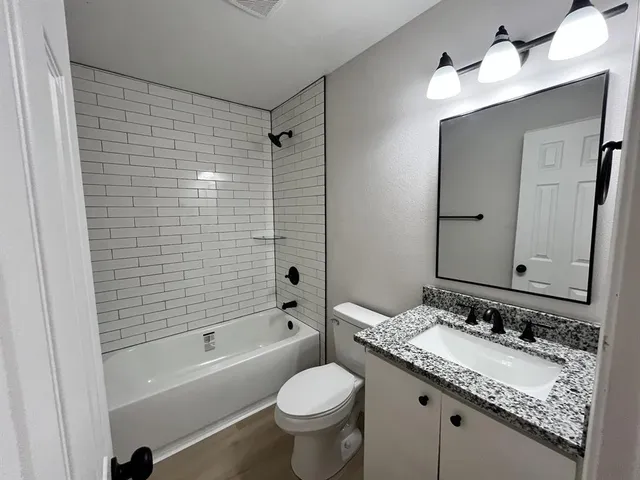 a bathroom with a granite countertop sink toilet and shower