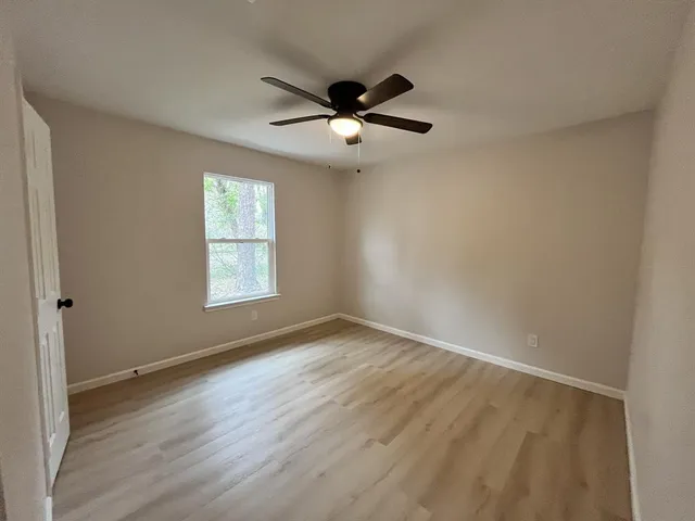 an empty room with windows and ceiling fan