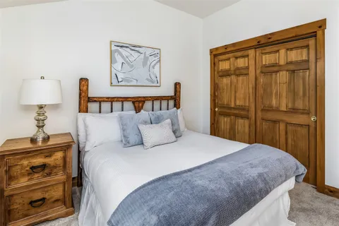 a bedroom with a bed and a lamp on dresser