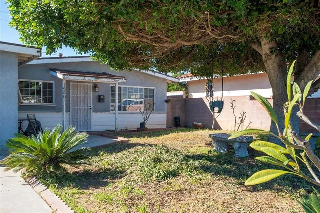 a backyard of a house with table and chairs under an large tree