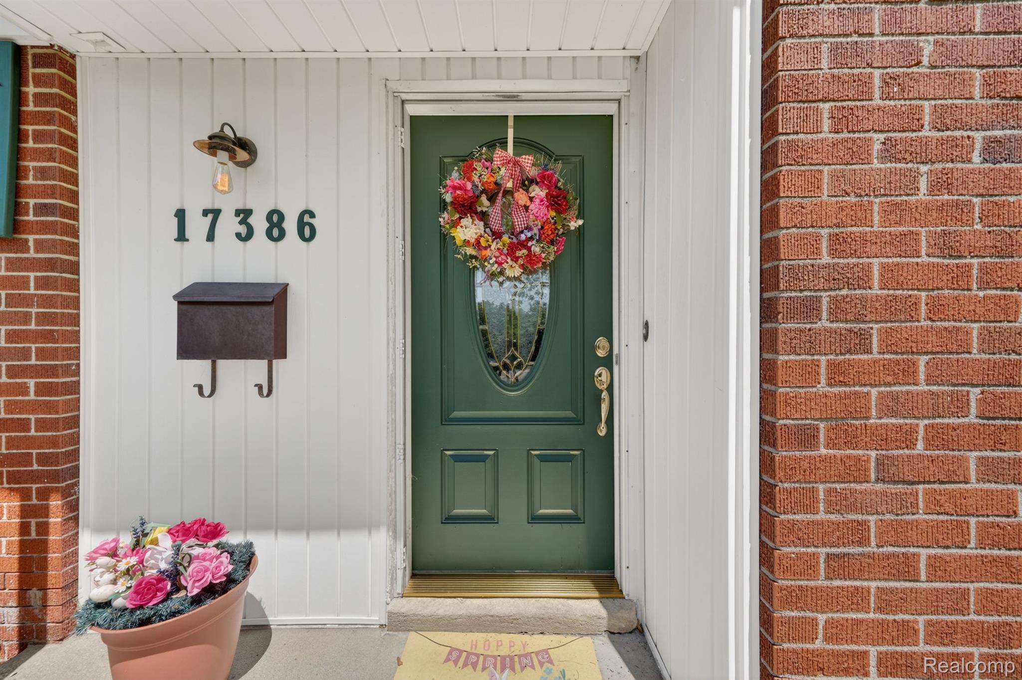 17386 Beverly Road Franklin, MI 48025 - Photo 4 of 28 Front entrance featuring a green paneled door with an oval glass insert, brass hardware, and a white vertical siding surround