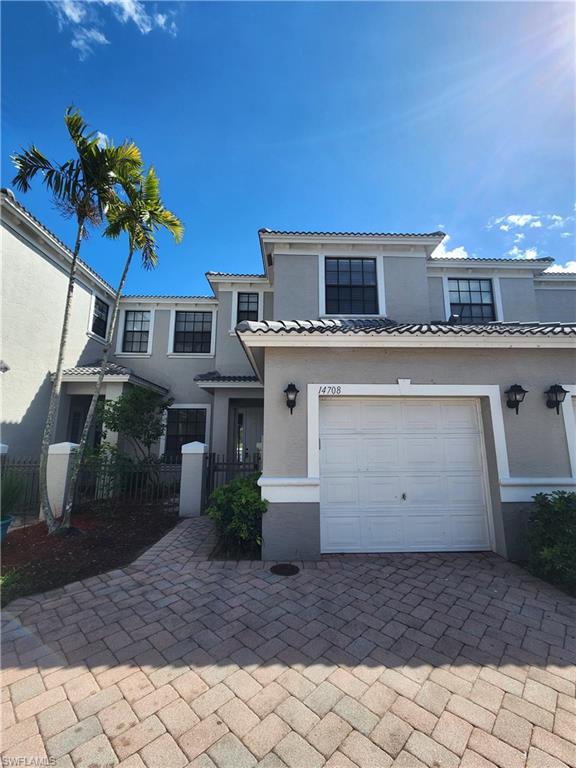 Mediterranean / spanish house featuring stucco siding, decorative driveway, an attached garage, and a tiled roof