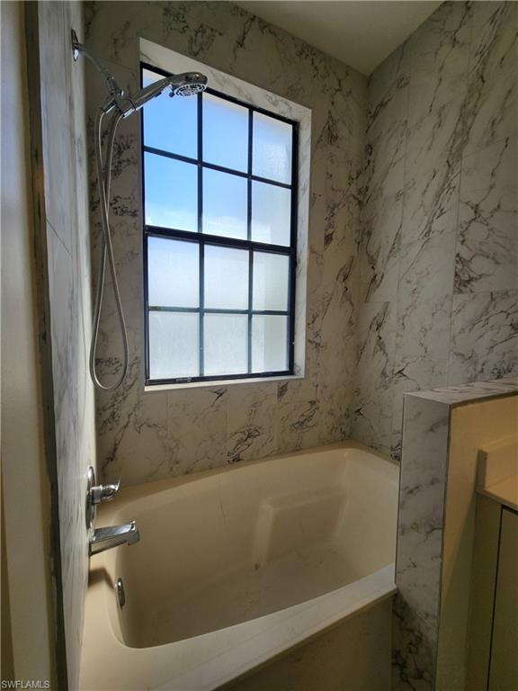 14708 Sutherland Avenue Naples, FL 34119 - Photo 14 of 24 Bathroom featuring vanity and a combined bath / shower with marble appearance