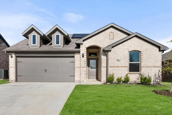 a view of a white house with a small yard and large tree