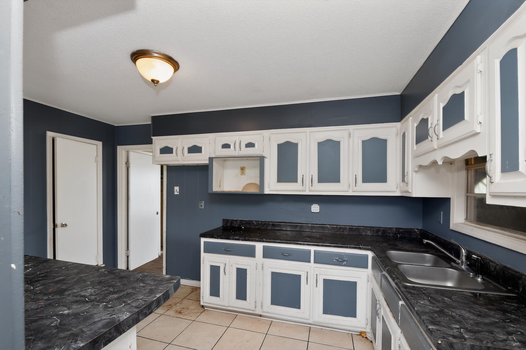 645 Parkrose Road Memphis, TN 38109 - Photo 10 of 32 Kitchen featuring a double basin stainless steel sink, dark countertops, white upper cabinetry, and white lower cabinetry with blue paneling