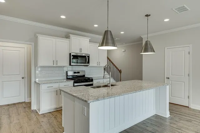 a kitchen with granite countertop a stove a sink and a wooden floor