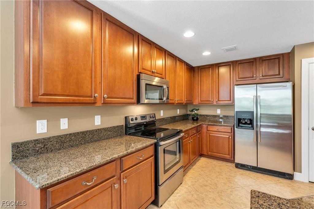12905 New Market Street, Unit 102 Fort Myers, FL 33913 - Photo 10 of 30 a kitchen with stainless steel appliances granite countertop wooden cabinets a refrigerator a sink a stove a washer dryer and a refrigerator