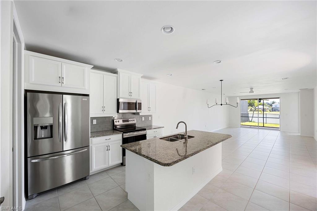 14799 Edgewater Circle Naples, FL 34114 - Photo 11 of 35 a kitchen with stainless steel appliances granite countertop a sink stove and refrigerator