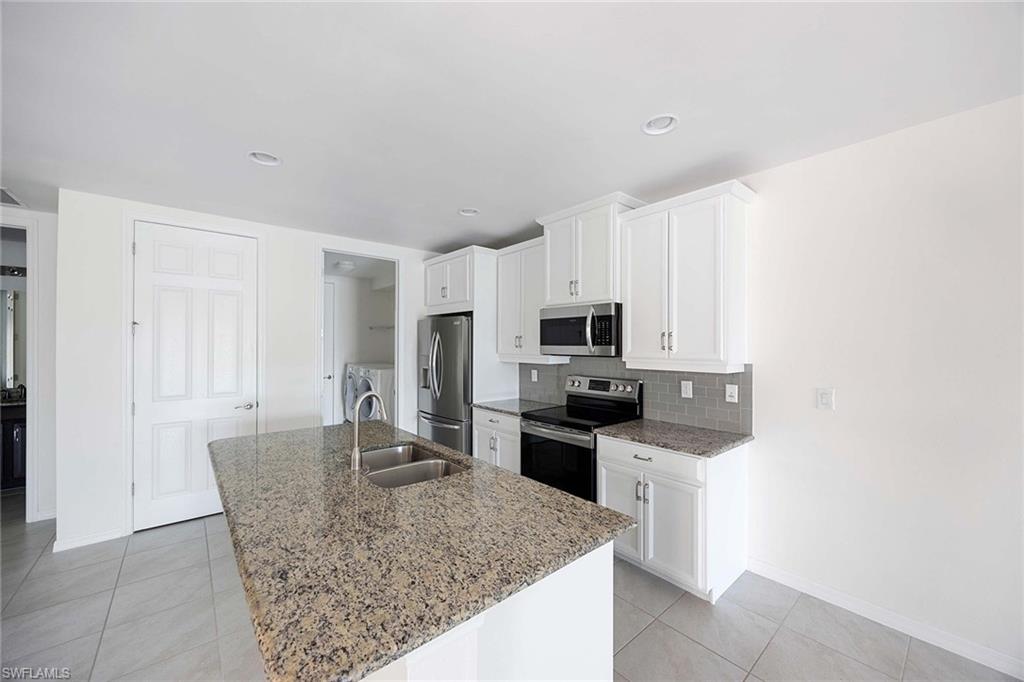 14799 Edgewater Circle Naples, FL 34114 - Photo 10 of 35 a kitchen with stainless steel appliances granite countertop a sink stove and refrigerator