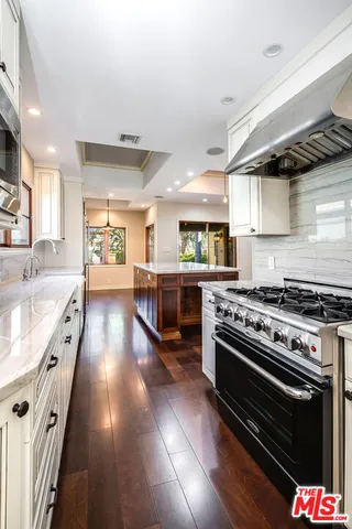 a kitchen with stainless steel appliances a stove a sink dishwasher and cabinets with wooden floor