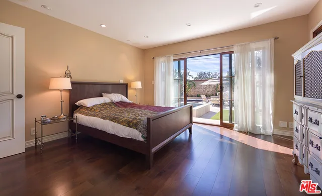 a bedroom with a bed lamp on table and a large window