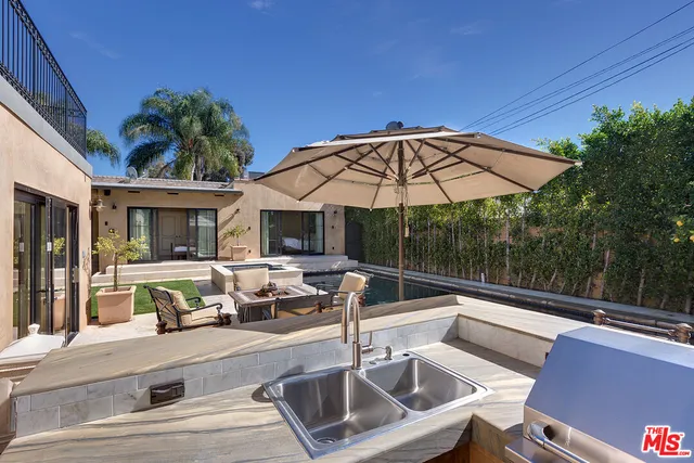 a view of a patio with couches table and chairs under an umbrella with a fire pit