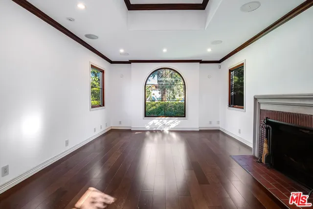 an empty room with wooden floor fireplace and windows