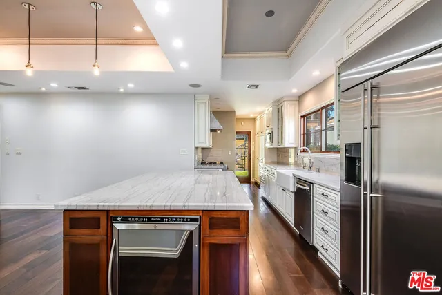 a kitchen with kitchen island a counter top space a sink stainless steel appliances and cabinets