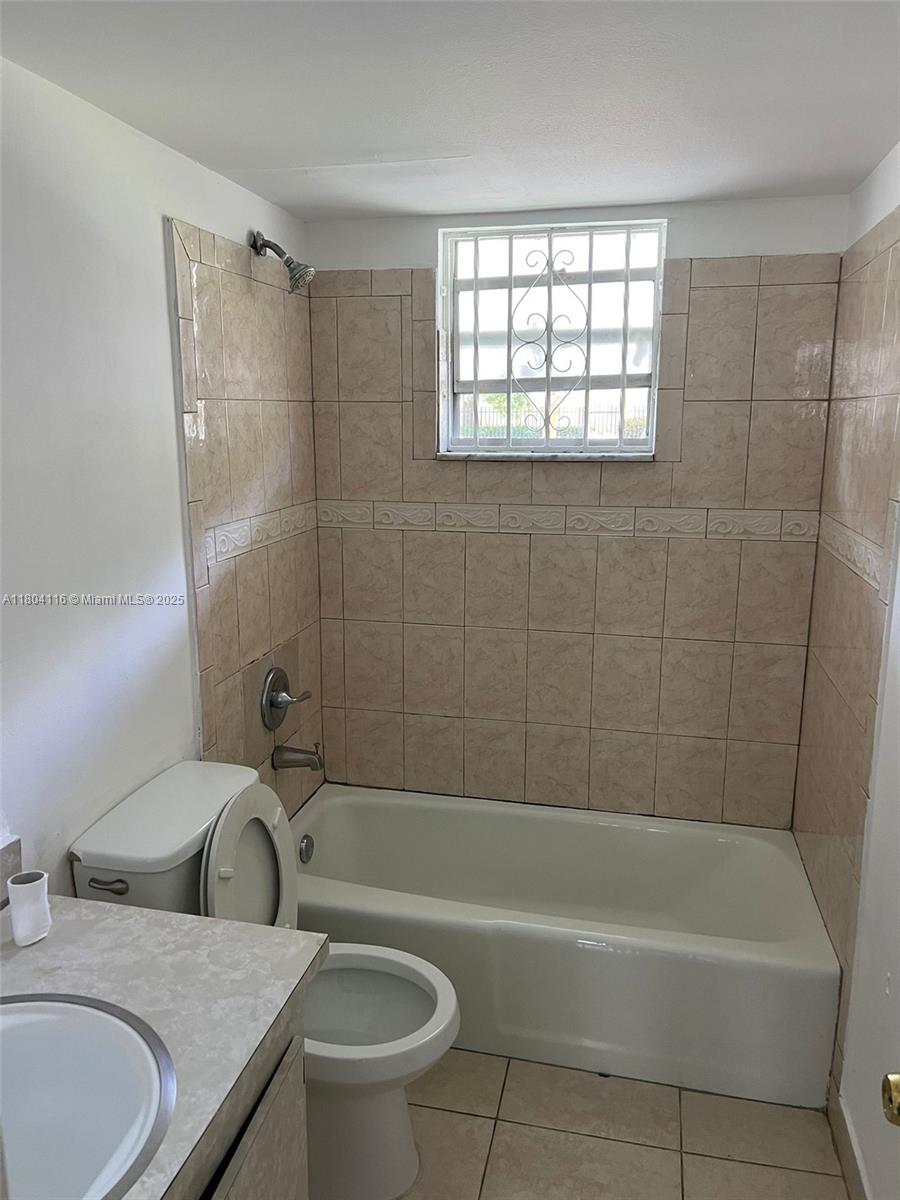 220 Southwest 9th Avenue, Unit 117 Hallandale Beach, FL 33009 - Photo 3 of 14 a bathroom with a granite countertop sink a toilet and bathtub