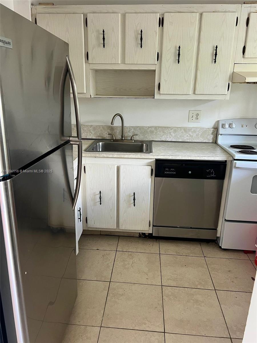220 Southwest 9th Avenue, Unit 117 Hallandale Beach, FL 33009 - Photo 9 of 14 a kitchen with a refrigerator sink and cabinets
