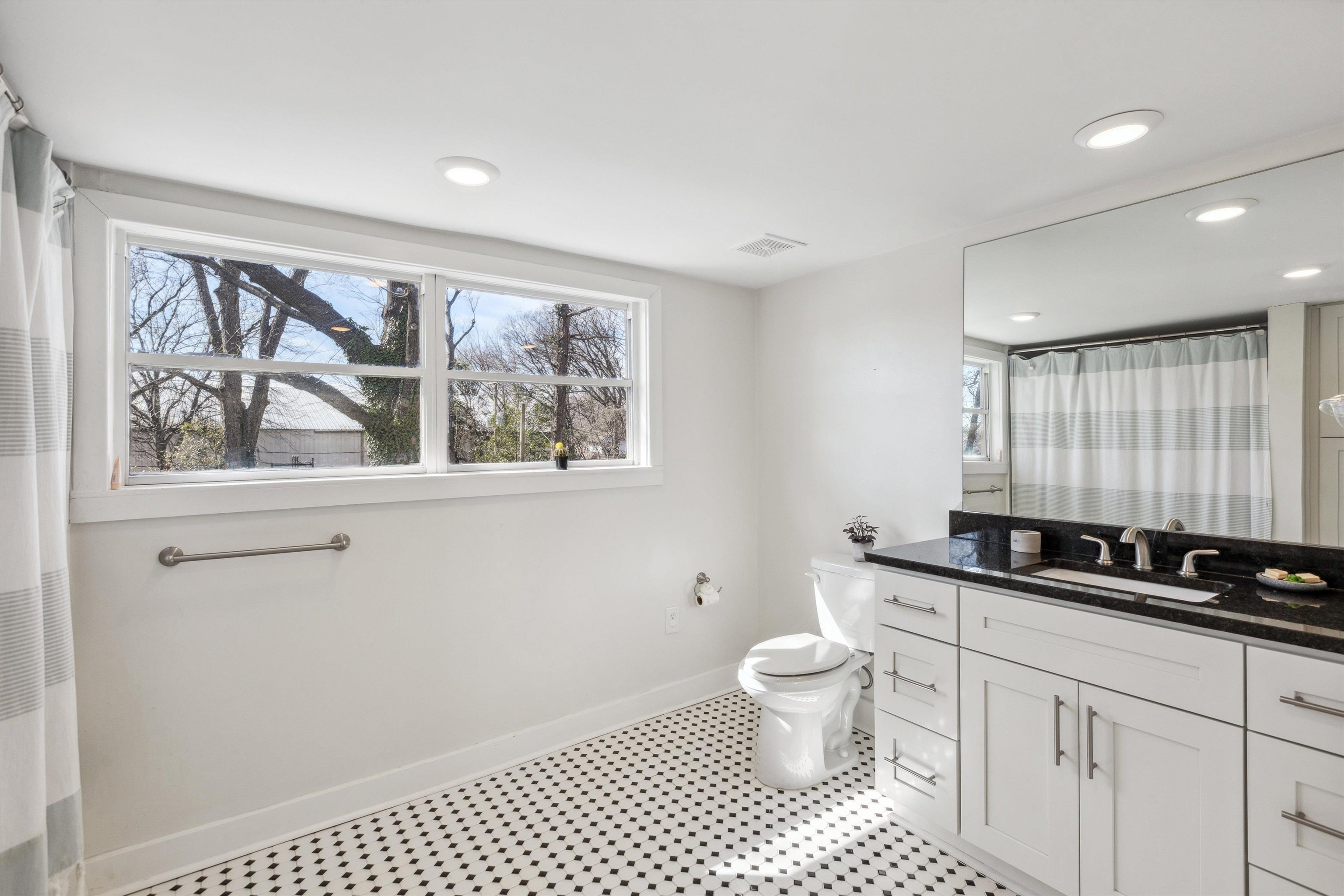 779 Roland Street Memphis, TN 38104 - Photo 17 of 29 a bathroom with a double vanity sink a toilet a mirror and a window