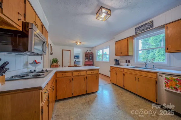 a large kitchen with stainless steel appliances granite countertop a sink dishwasher stove and wooden cabinets