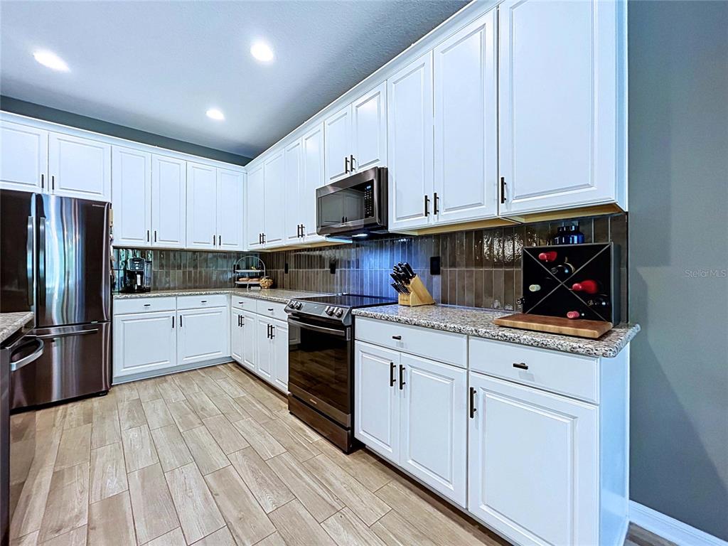 18078 Romanesque Court Spring Hill, FL 34610 - Photo 16 of 81 a kitchen with granite countertop white cabinets and stainless steel appliances