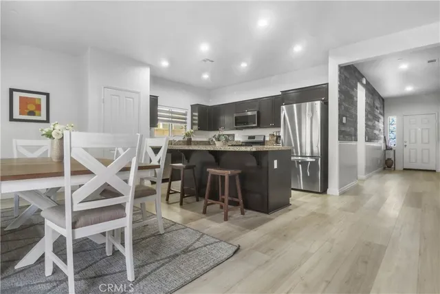 a kitchen with stainless steel appliances kitchen island granite countertop a table chairs sink and cabinets