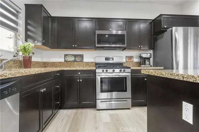 a kitchen with stainless steel appliances granite countertop a stove a sink and a microwave