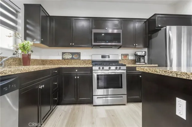 a kitchen with stainless steel appliances granite countertop a stove a sink and a microwave