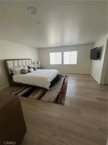 a spacious bedroom with a bed and wooden floor