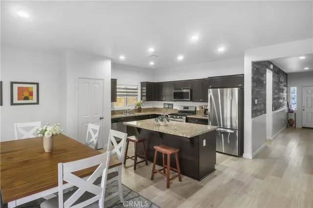 a kitchen with stainless steel appliances a dining table chairs refrigerator and microwave