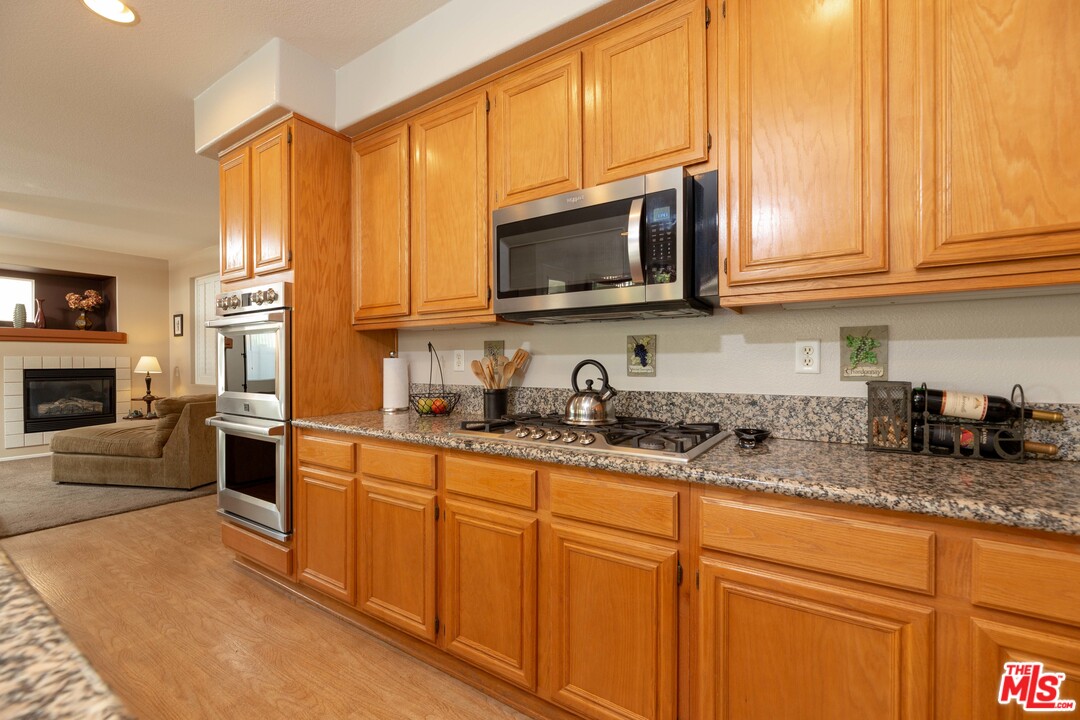 6847 Raspberry Court Eastvale, CA 92880 - Photo 18 of 49 a kitchen with stainless steel appliances granite countertop a sink a stove a microwave and cabinets