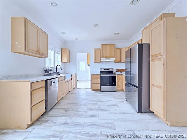 a large kitchen with stainless steel appliances granite countertop a stove top oven a refrigerator and a sink