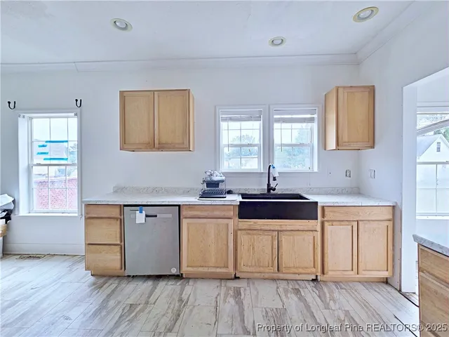 a kitchen with granite countertop a stove a sink and white cabinets with wooden floor