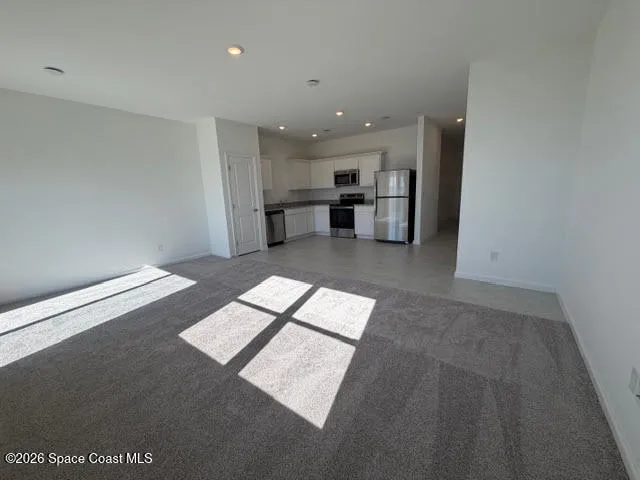 a living room with stainless steel appliances furniture and a kitchen view