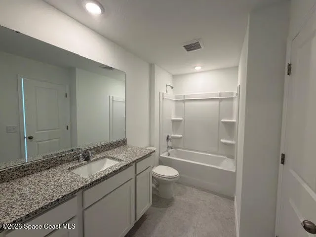 a bathroom with a granite countertop sink a toilet a mirror and shower