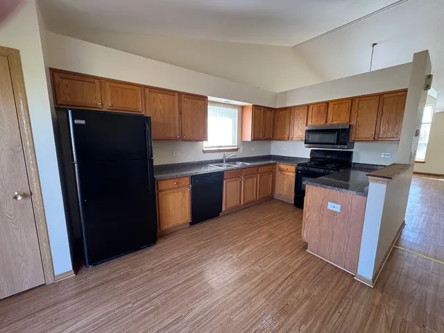 a kitchen with stainless steel appliances granite countertop a refrigerator a sink dishwasher a stove and white countertops with wooden floor