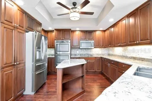 a kitchen with kitchen island granite countertop a refrigerator stove and sink
