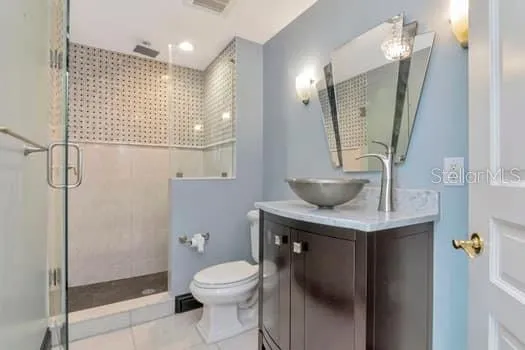 a bathroom with a granite countertop sink a toilet a mirror and shower