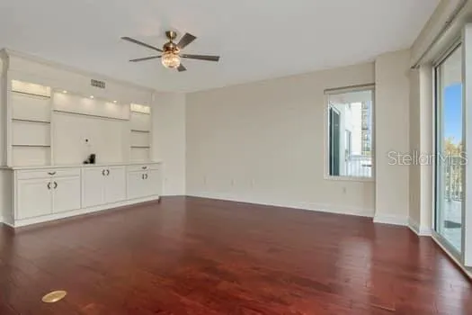 an empty room with wooden floor and a ceiling fan