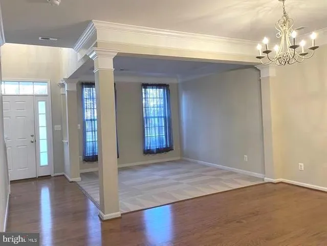 a view of an empty room with wooden floor and a chandelier