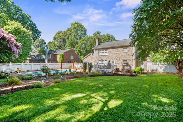 a backyard of a house with table and chairs plants and large tree