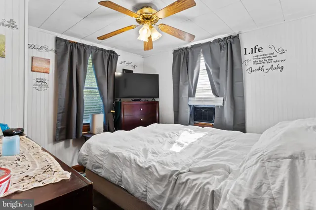 a bedroom with a bed and a flat tv screen on dresser