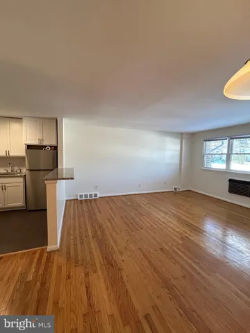 a view of empty room with wooden floor and window