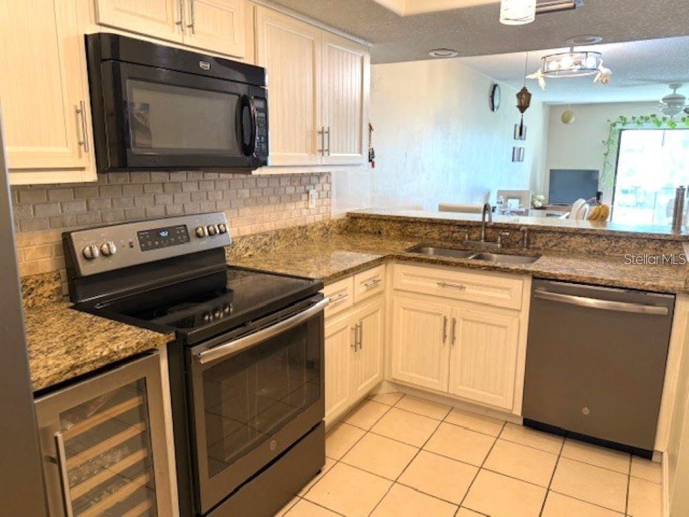 108 Nina Way, Unit 3 Oldsmar, FL 34677 - Photo 9 of 25 a kitchen with granite countertop a sink stove and microwave
